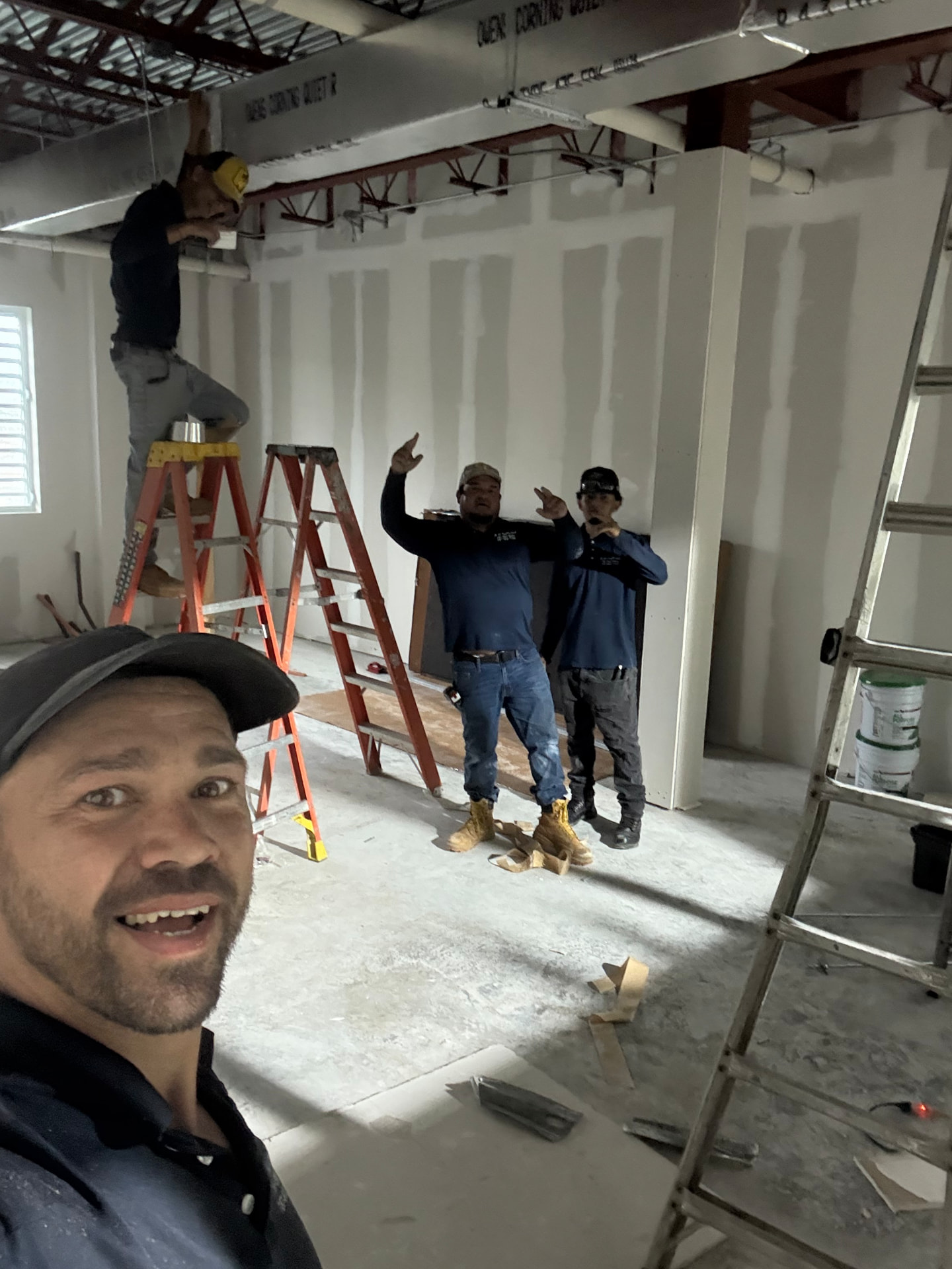 Equipo de JL en una obra de interiores con paredes de gypsum board recién encintadas y masilladas