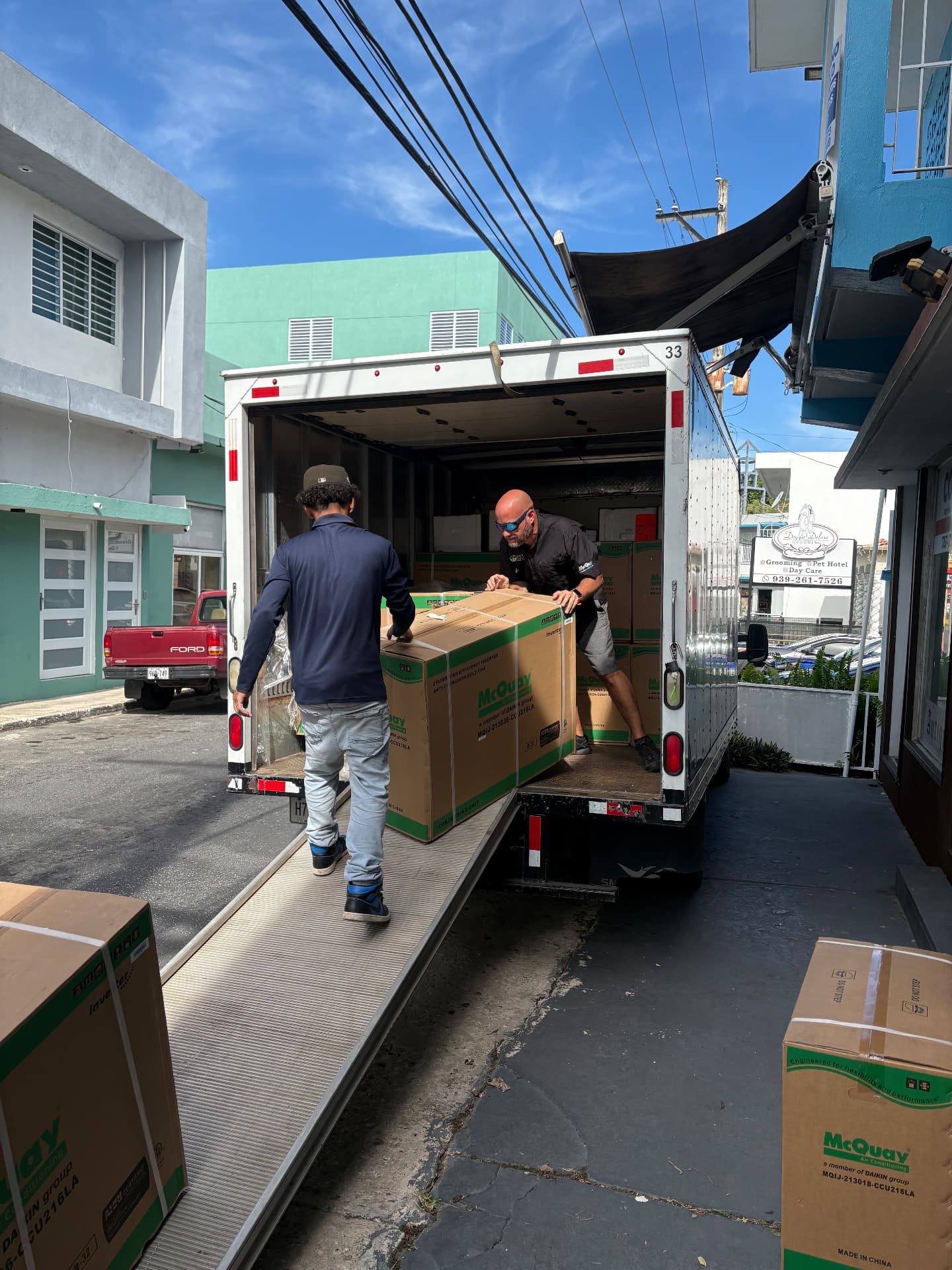 Equipo de JL descargando cajas de unidades condensadoras de aire acondicionado de un camión